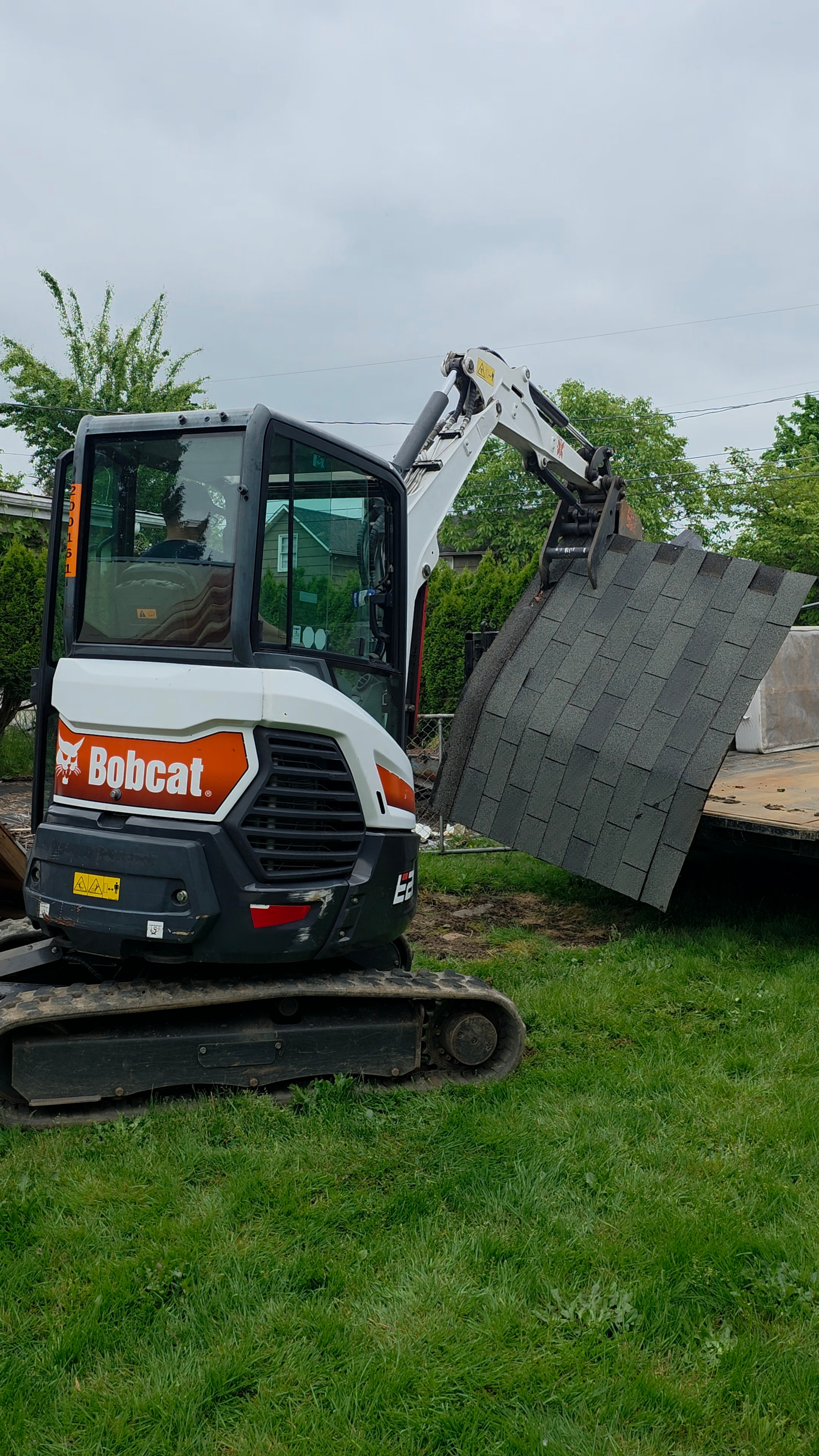 Bobcat loading roofing material and debris onto truck