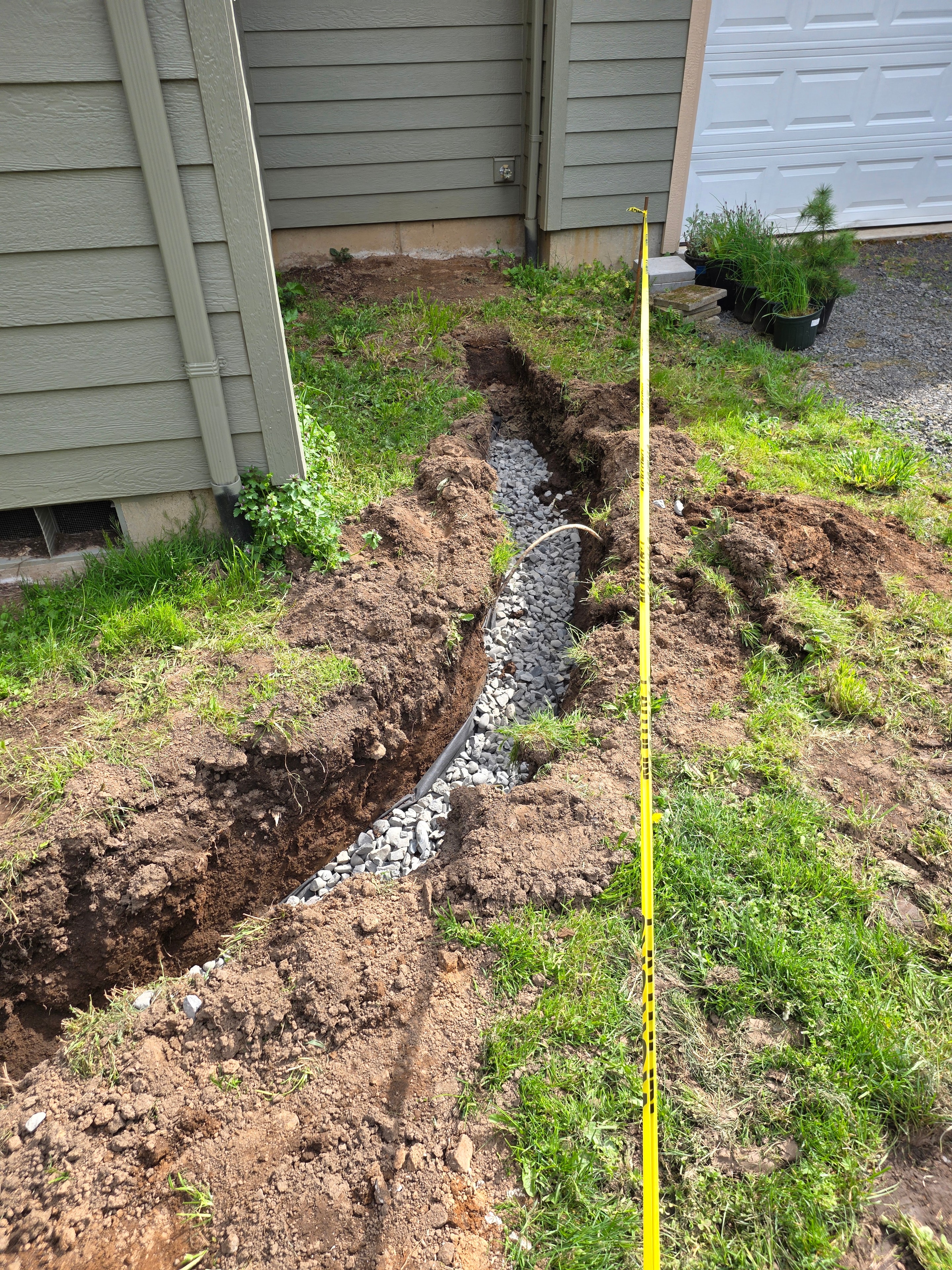 Trench excavation through front yard for French drain installation