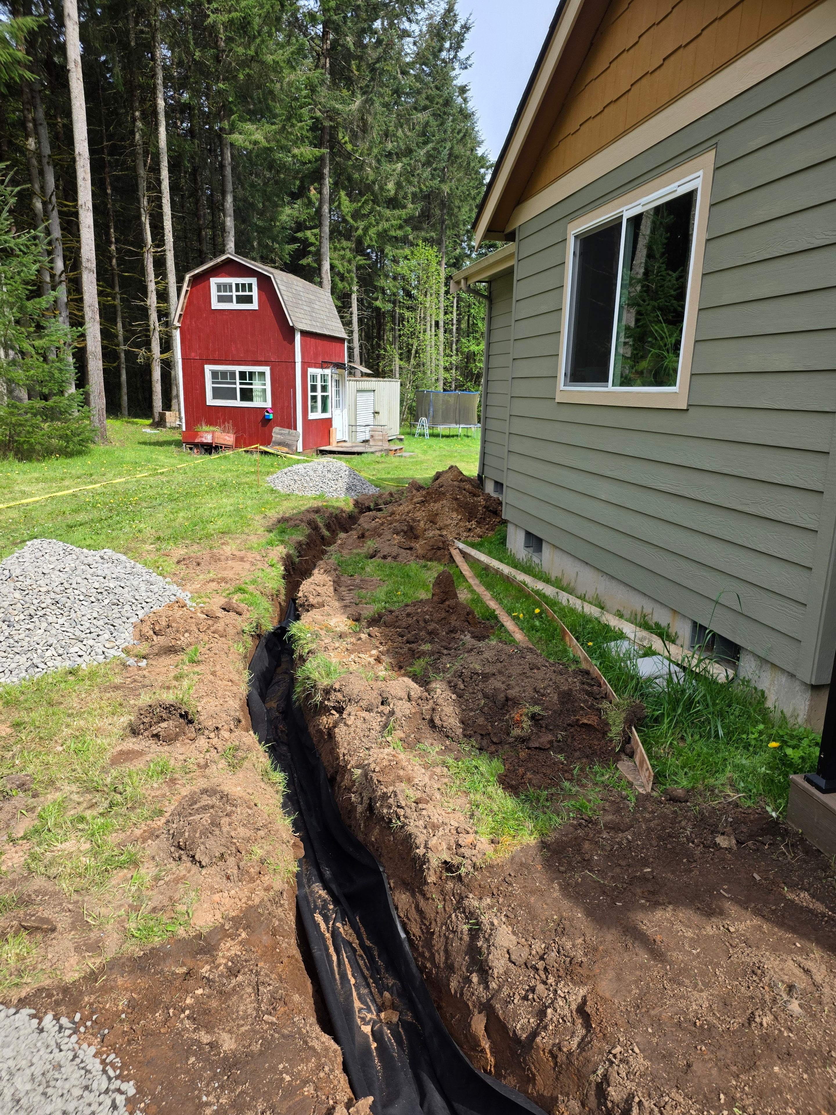 French drain trench filled with drain rock before backfill